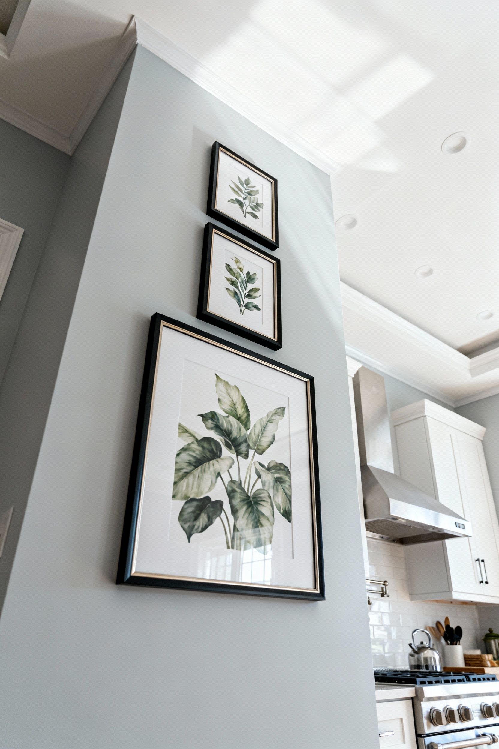 Vertical arrangement of three botanical prints in tiered fashion on a modern kitchen wall, designed to draw the eye upwards and enhance perceived ceiling height.